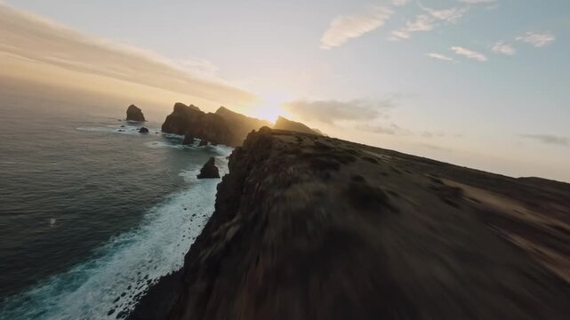 FPV Drone Flight Along Coastal Cliff Edge Toward Sunset Over Sea Stacks
