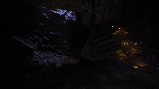 Flickering candles in rocky hollow memorial mood soft amber light slicing through cool shadow reflection in shallow pool quiet tribute captured in still frame