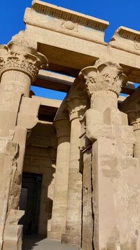 Kom Ombo temple ruins with double columns and composite capitals against clear blue sky in Egypt, ancient Ptolemaic architecture dedicated to Sobek and Horus with damaged walls