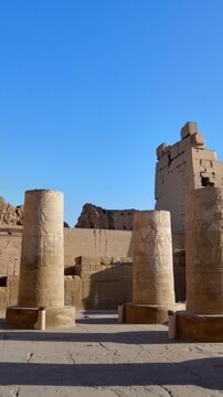 Kom Ombo temple columns with composite capitals and hieroglyphic carvings viewed from below against blue sky in Egypt, upward perspective of ancient sandstone architecture
