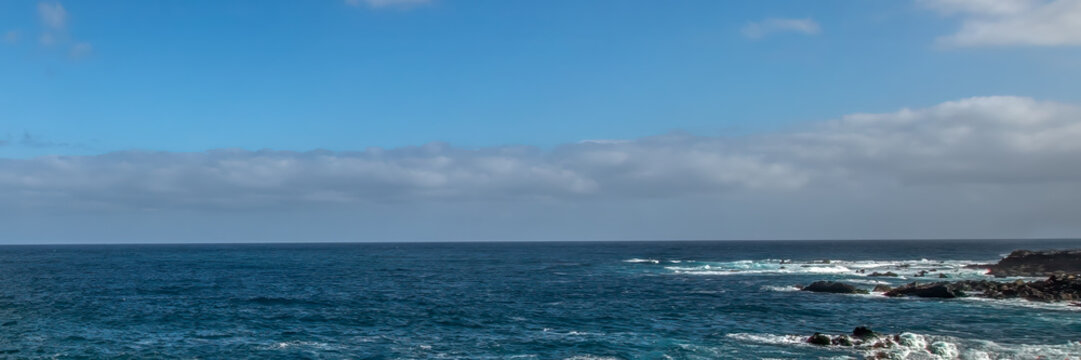 Atlantic ocean waves crashing against rocky coastline under blue sky with copy space for travel background