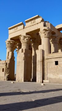 Kom Ombo temple ruins with double columns and composite capitals against clear blue sky in Egypt, ancient Ptolemaic architecture dedicated to Sobek and Horus with damaged walls