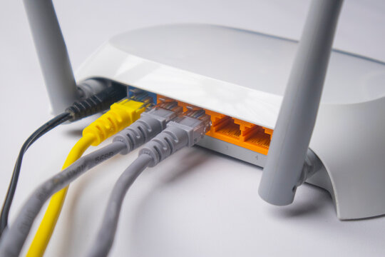 Close-up of the back panel of a white wireless router, featuring a black power cable and a yellow Ethernet cable connected to the WAN port, with four empty LAN ports visible.