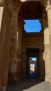 Kom Ombo temple columns with composite capitals and hieroglyphic carvings viewed from below against blue sky in Egypt, upward perspective of ancient sandstone architecture