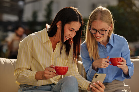 Women friends laughing looking at smartphone together