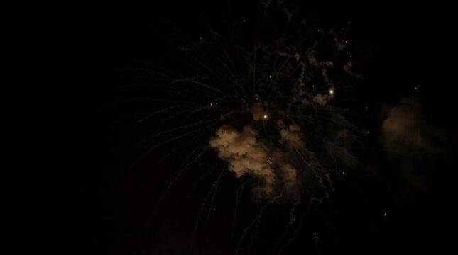 Gold fireworks exploding with smoke against a dark night sky background