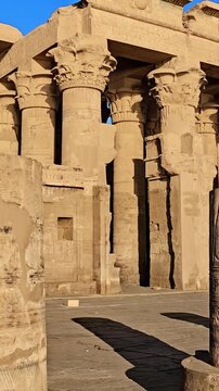 Kom Ombo temple ruins with double columns and composite capitals against clear blue sky in Egypt, ancient Ptolemaic architecture dedicated to Sobek and Horus with damaged walls