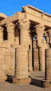 Kom Ombo temple ruins with double columns and composite capitals against clear blue sky in Egypt, ancient Ptolemaic architecture dedicated to Sobek and Horus with damaged walls
