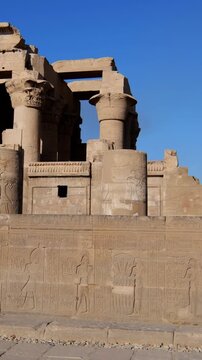 Kom Ombo temple ruins with double columns and composite capitals against clear blue sky in Egypt, ancient Ptolemaic architecture dedicated to Sobek and Horus with damaged walls