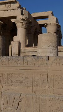 Kom Ombo temple ruins with double columns and composite capitals against clear blue sky in Egypt, ancient Ptolemaic architecture dedicated to Sobek and Horus with damaged walls