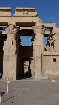 Kom Ombo temple ruins with double columns and composite capitals against clear blue sky in Egypt, ancient Ptolemaic architecture dedicated to Sobek and Horus with damaged walls