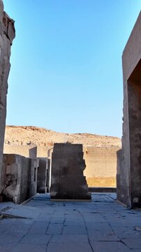 Kom Ombo temple columns with composite capitals and hieroglyphic carvings viewed from below against blue sky in Egypt, upward perspective of ancient sandstone architecture