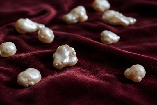 Irregular pearl nodules scattered on velvet fabric in close-up with soft texture and shallow depth.