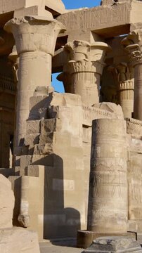 Kom Ombo temple ruins with double columns and composite capitals against clear blue sky in Egypt, ancient Ptolemaic architecture dedicated to Sobek and Horus with damaged walls