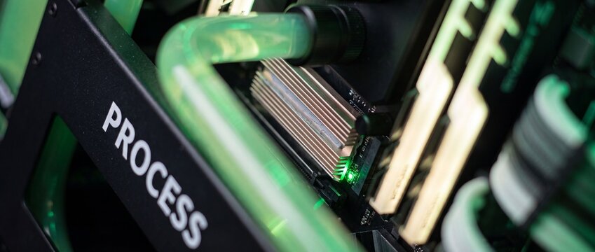 Liquid cooled computer processor motherboard with green water cooling loop system showing hardware components, RAM, heatsink details in custom gaming PC desktop setup for technology concept background