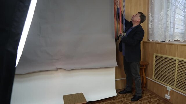 A male photographer lowers a gray paper backdrop in a professional studio.