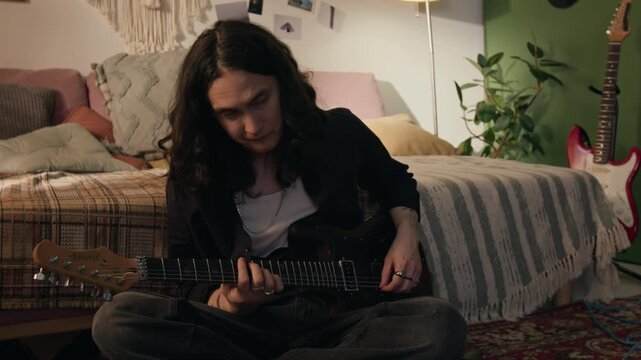 Young man sitting on floor in bedroom, playing electric guitar. Footage for commercials promoting music lessons, creative hobbies, or youth lifestyle brands