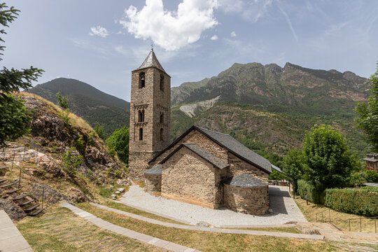 Boi, Spain. General view of the Romanesque church of Sant Joan de Boi showing two original absidioles, a reconstructed quadrangular central apse, a stone bell tower and a mountain background