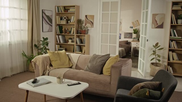 Full no people shot of modern living room displaying beige sofa, coffee table, and bookshelves. Ideal for real estate marketing, interior design promotions, or home staging advertisements