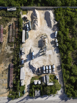 Aerial view of Ergon Asfaltos Progreso industrial facility with concrete mixers, storage tanks, and piles of construction materials in Progreso, Yucatan, Mexico.