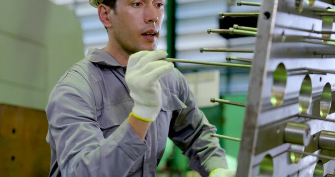 Asian male technician inspects metal fixture at close range, checking guide rod placement, component detail, safety condition, precision setup, maintenance workflow in , slow motion.