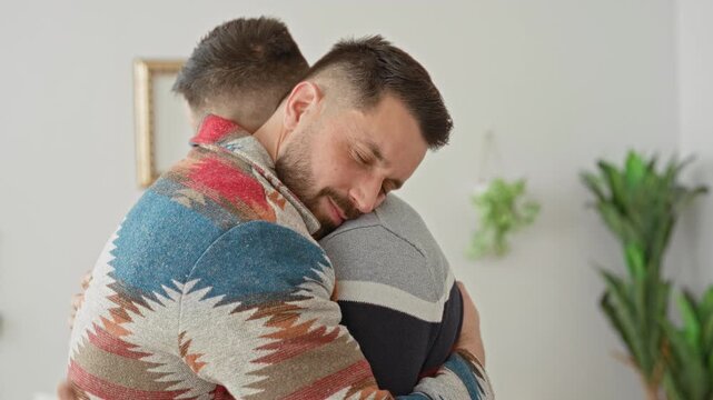 Man hugging with hand on back and eyes closed, patterned sweater visible, in building living room; love support comfort.