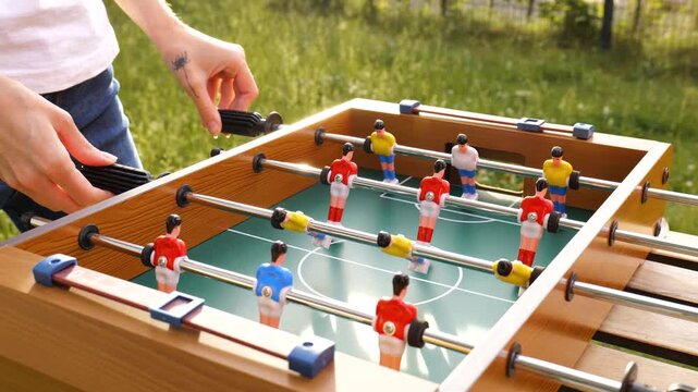 Two people playing table football outdoors in a garden setting, expressing universal playfulness and a youthful spirit.
