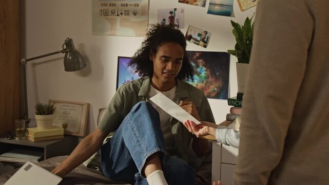 Handheld shot of African American teenager receiving college acceptance letter from Caucasian mother, reacting with excitement and hugging parents. Ideal for student success and education campaigns