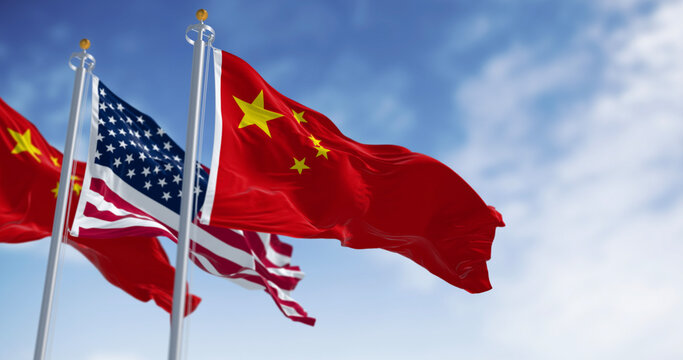 National flags of China and the United States waving in the wind on a clear day