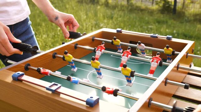 Two people playing table football outdoors in a garden setting, expressing universal playfulness and a youthful spirit.	