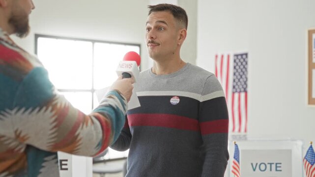 Man speaking into a news microphone while holding a ballot paper and wearing an i voted sticker inside polling station building; civic pride.