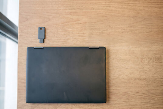 Hardware Security Key with Closed Laptop on Wooden Table, Cyber Security Concept