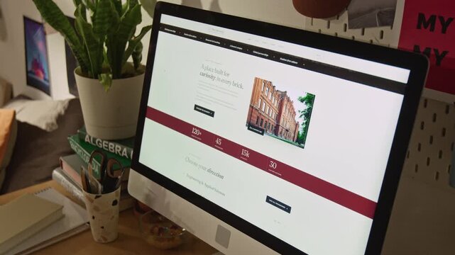 No people close up shot of computer monitor displaying university website on student desk with textbooks. For commercial videos promoting online education, college admissions, e-learning platforms