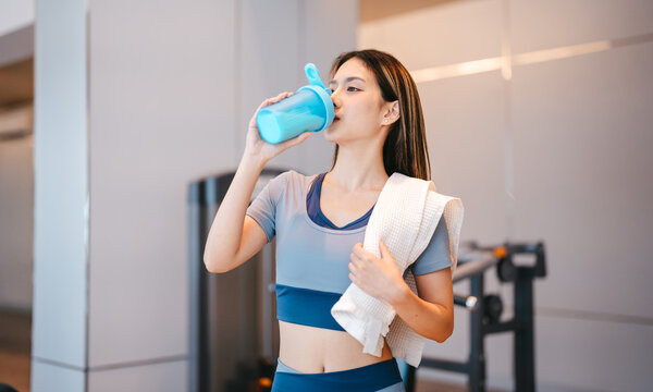 Beautiful young asian woman, wear sportswear drinking protein shake post workout exercise at indoor gym