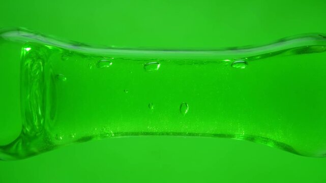 Stretched green slime gel with bubbles on green background.