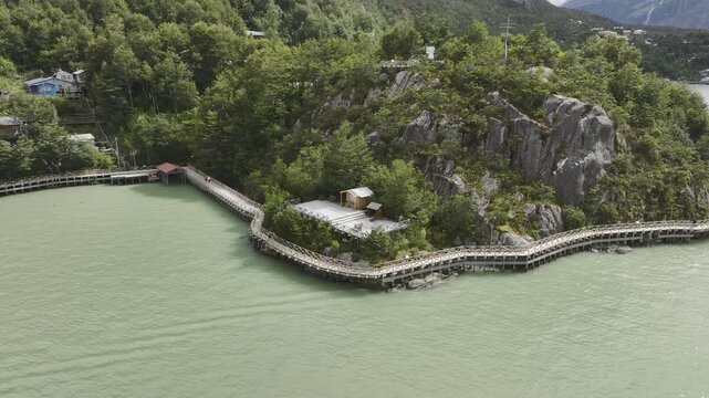Aerial view of the wooden boardwalks winding along a rocky cliffside and glacial water in the remote coastal village of Caleta Tortel, Patagonia, Chile.