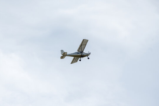 Corby, United Kingdom &ndash; July 1, 2026: Light aircraft flying over airfield against cloudy sky, editorial
