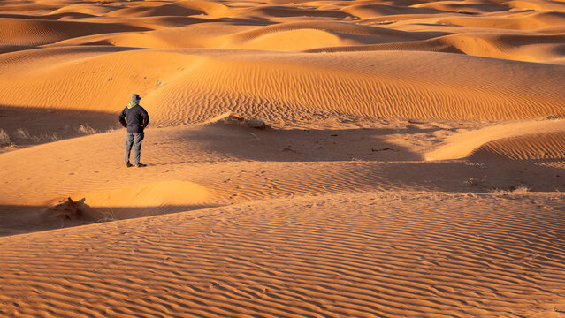 lonely male figure in a sand dunes field, dusty and windy morning in San Rafael Swell area in Utah (Lower San Rafael Road), panoramic web banner