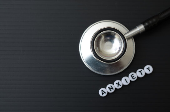 Medical stethoscope with anxiety text on black background for mental health awareness concept.