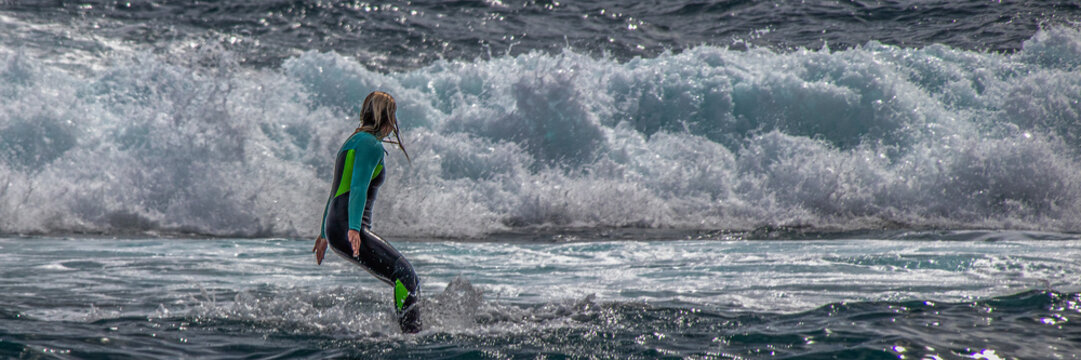 Surfer woman in wetsuit standing in ocean waves during active water sports training and focused adventure