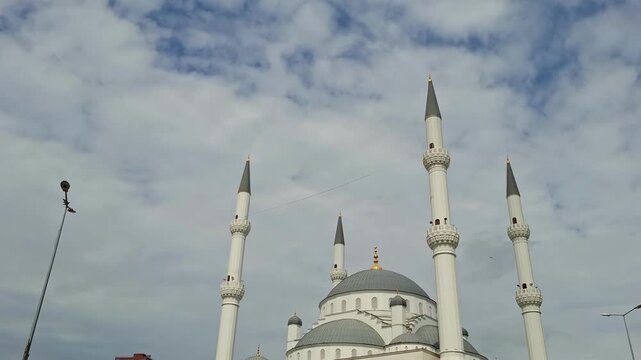 Minarets and dome of Basaksehir Millet Camii mosque against a cloudy blue sky in Istanbul, Turkey