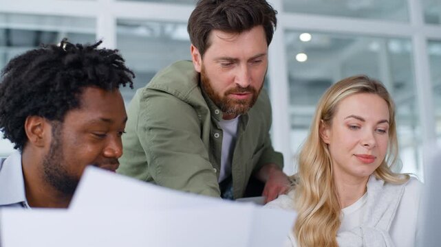 Work team three multiracial business managers discussing documents working growth progress trading market target result analyzing papers smiling carefree motivated multiethnic businesspeople in office