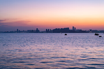 Obraz premium Fishing Boats on Sea at Dusk with City Skyline Gradient, Qingdao, China