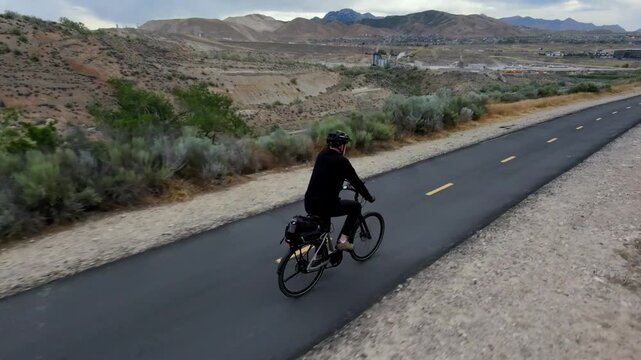 Man cycling to work along a backroads trail on an e-bike at daytime
