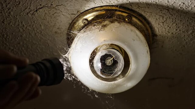 Water sprays from flashlight onto ceiling light fixture in dark room with focused light. Action captures importance of maintenance and repairs. Concept of plumbing, home improvement, repair services