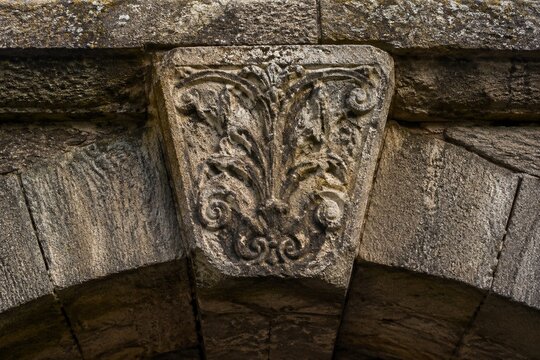 Ancient stone arch bridge keystone with intricate weathered carvings.