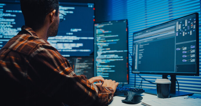 Close up young Male programmer hands typing on keyboard in dark home office at night. AI technology, cybersecurity, software developer, freelance innovation, database system, digital network concept.