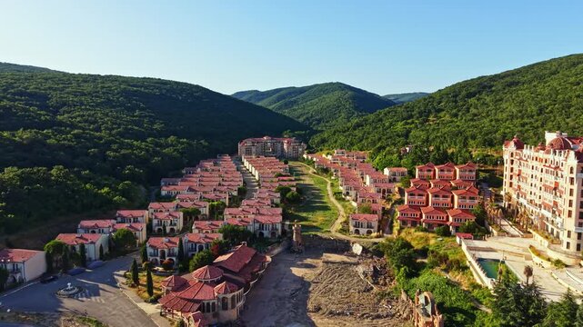 Elenite city shows homes affected by the flood. Some buildings are damaged, and the ground looks altered. The area has trees on hills in the background under clear sky.