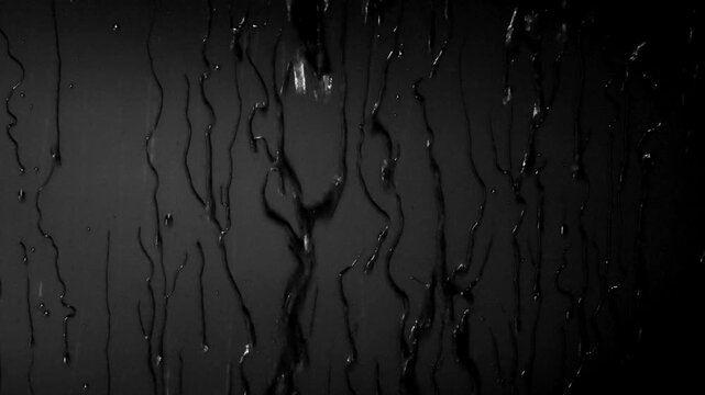 Water drops slide down a black surface in a series of four frames showing motion