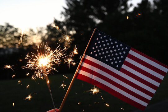 Holding sparklers with an American Flag to celebrate patriotic holiday - the 4th of July USA Independence Day